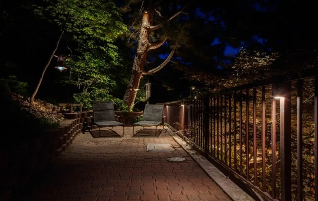 a brick walkway with a metal fence at night.