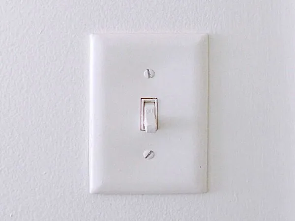 a white light switch on a white wall.