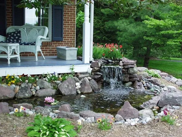 a house with a small waterfall in the front yard.