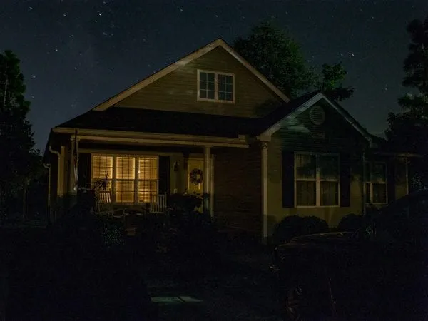 a house lit up at night with the lights on.