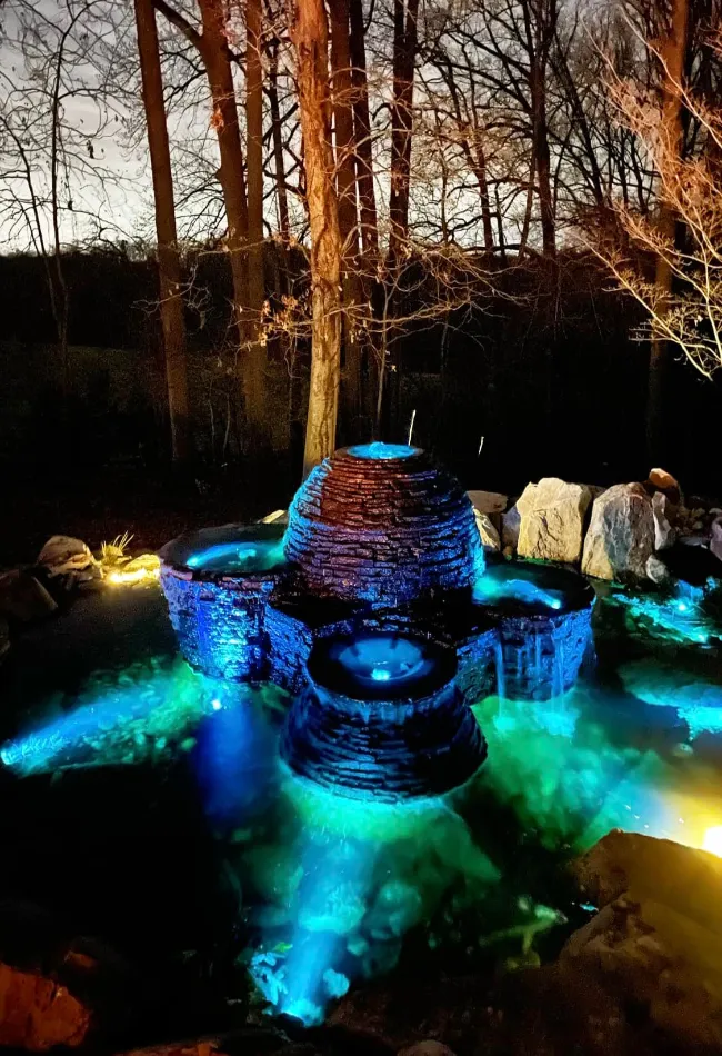 Some stacked slate urn fountains at night with blue lights