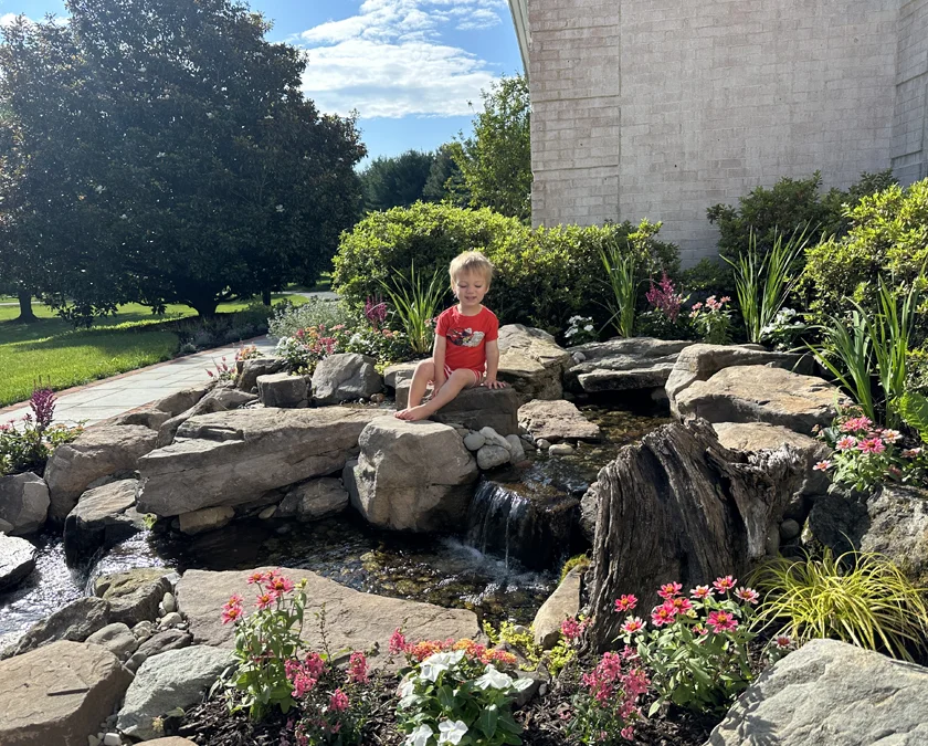 New pond with little boy sitting on rocks